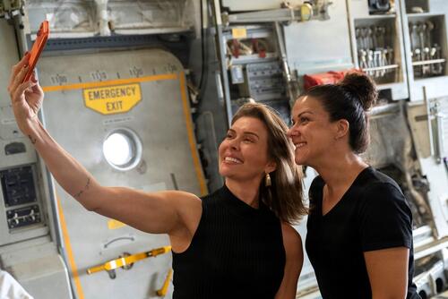 Two military spouses take a selfie together inside an aircraft.
