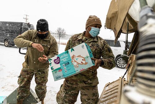 U.S. Army Sgt. Courtney Hawthorne, left, assigned to 302nd Maneuver Enhancement Brigade, Westover Air Reserve Base, Massachusetts, hands a box of diapers to Sgt. George Alexander, right, assigned to 250th Transportation Company, El Monte, California, at Fort McCoy, Wisconsin, Dec. 28, 2021. (U.S. Army photo by Staff Sgt. Benjamin John, 302D Maneuver Enhancement Brigade Public Affairs NCOIC)